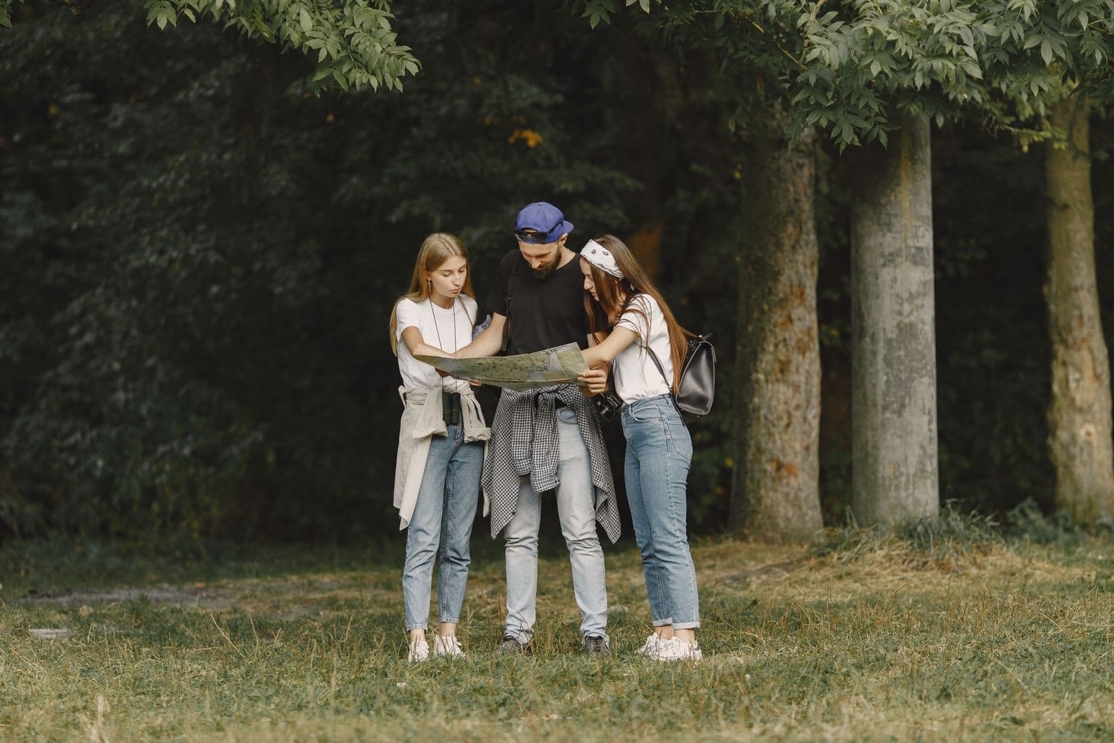 Friends reading one map together in a woodland clearing